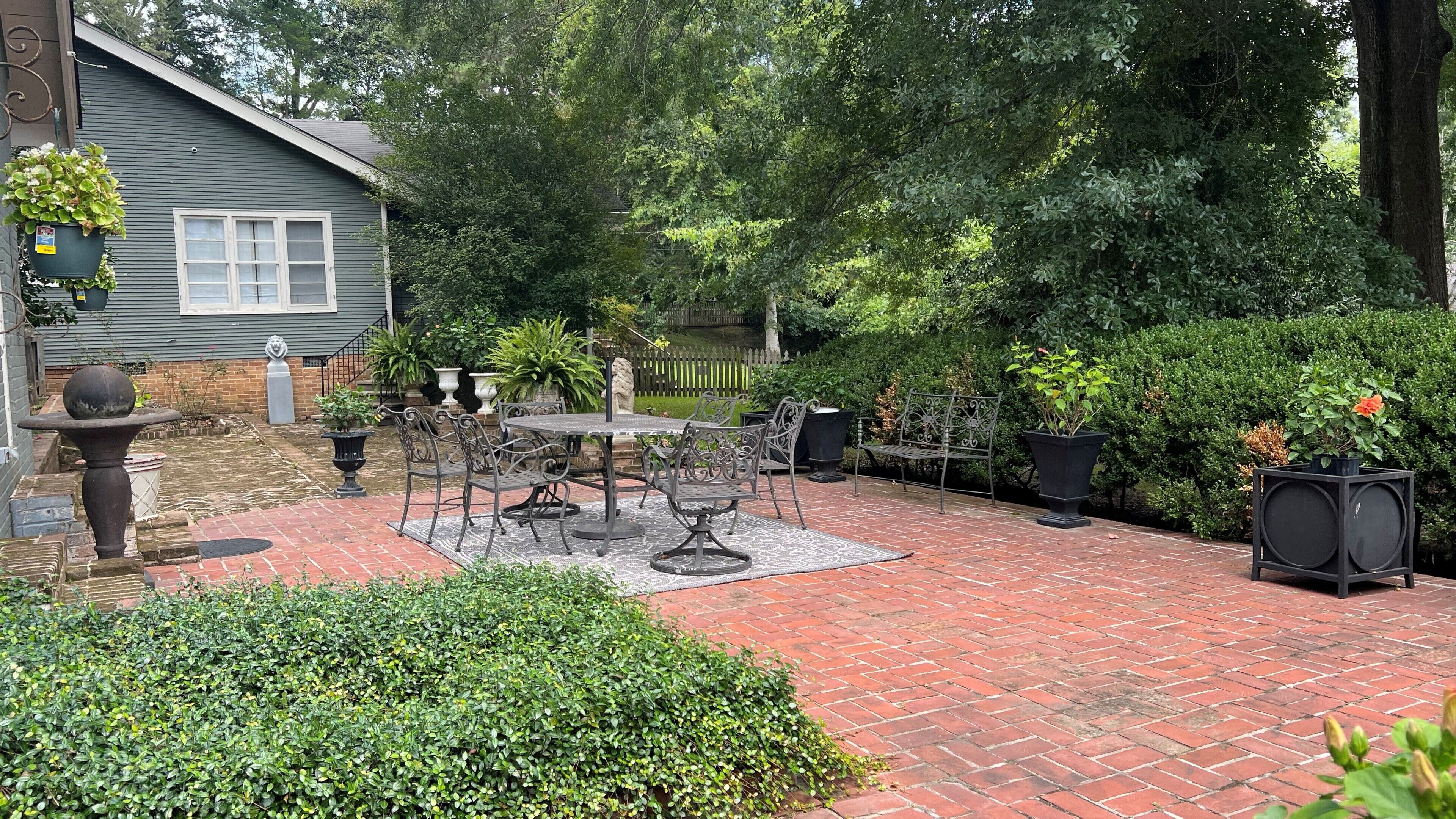 A patio with a brick floor, outdoor furniture, and potted plants.