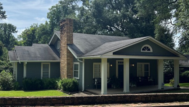 A two-story house with a brick chimney, a porch with white columns, and a green lawn. - Charming 3BR cottage, that borders the grounds of Historic Linden. (Natchez)
