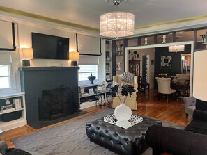 Una sala de estar con chimenea, televisor y candelabro.