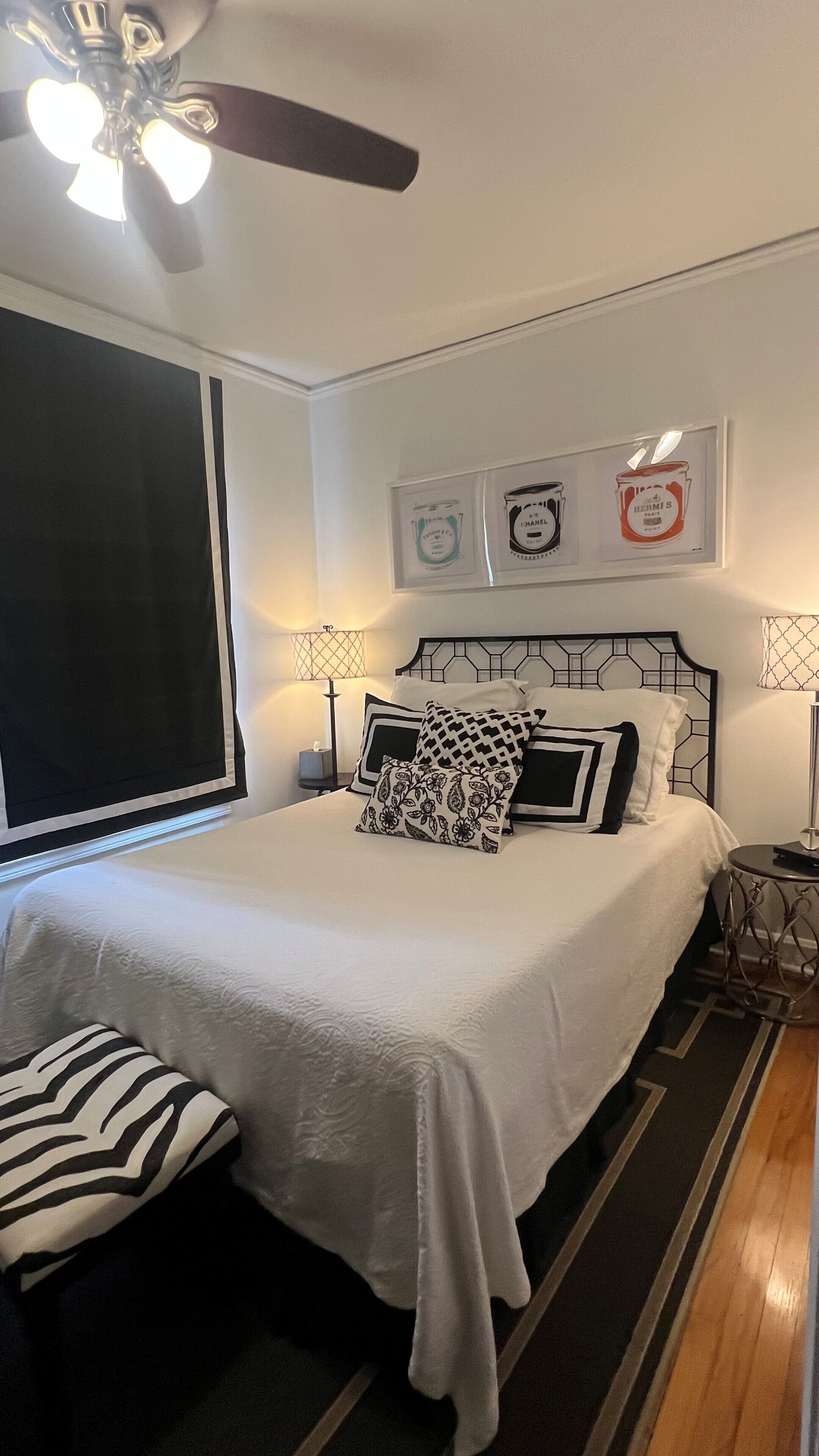 A bedroom with a bed, two bedside tables, a ceiling fan, and wall art.