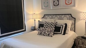 A bedroom with a bed, two bedside tables, a ceiling fan, and wall art. - Charming 3BR cottage, that borders the grounds of Historic Linden. (Natchez)