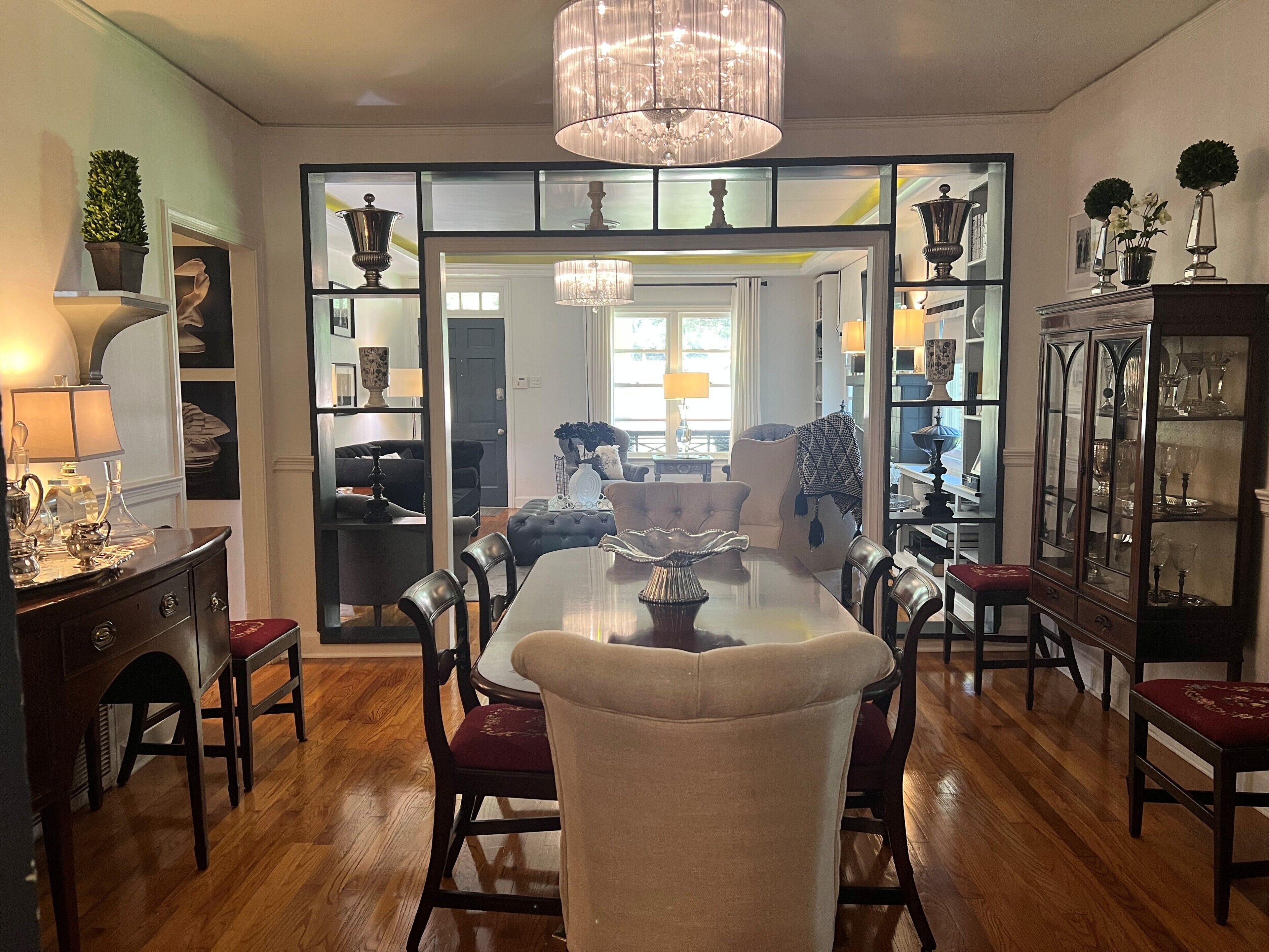 A dining area with a chandelier, a dining table, chairs, and a cabinet with glass doors.