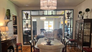 A dining area with a chandelier, a dining table, chairs, and a cabinet with glass doors. - Charming 3BR cottage, that borders the grounds of Historic Linden. (Natchez)