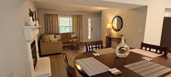 A living room with a sofa, a dining table with placemats, a lamp, and a vase.