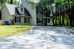 A two-story house with a front porch and a driveway leading to the entrance.