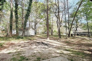 A rustic cabin surrounded by trees, with a dirt path leading to it.