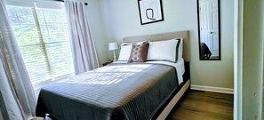 A neatly made bed with a patterned bedspread, a bedside lamp, and a framed picture on the wall.