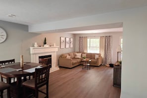 A living room with a fireplace, a dining table, and a sofa.