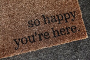 Alfombra de entrada con la inscripción 'so happy you're here'.