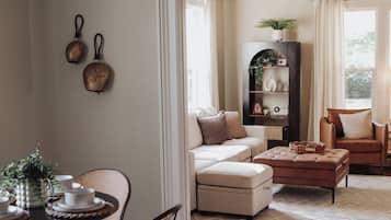 Een ruime woonkamer met een eethoek, met een zithoek, een salontafel en een eettafel met stoelen.