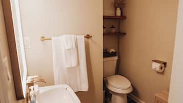 Een badkamer met een wit wastafelmeubel, toilet en handdoekhouder.