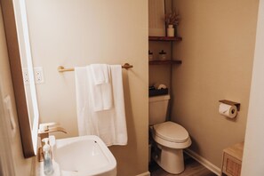 Et badeværelse med vask, toilet og håndklædestang.