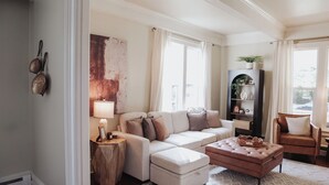 A living room with a sofa, ottoman, and a side table with a lamp.