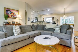 A modern living room with a sectional sofa, a round coffee table, and a kitchen in the background. - 2 Mi to Coligny Beach! HHI Home w/ Deck (Hilton Head Island)