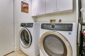 A laundry room with two front-loading washing machines, a small cabinet above, and a wall-mounted electrical outlet. - 2 Mi to Coligny Beach! HHI Home w/ Deck (Hilton Head Island)