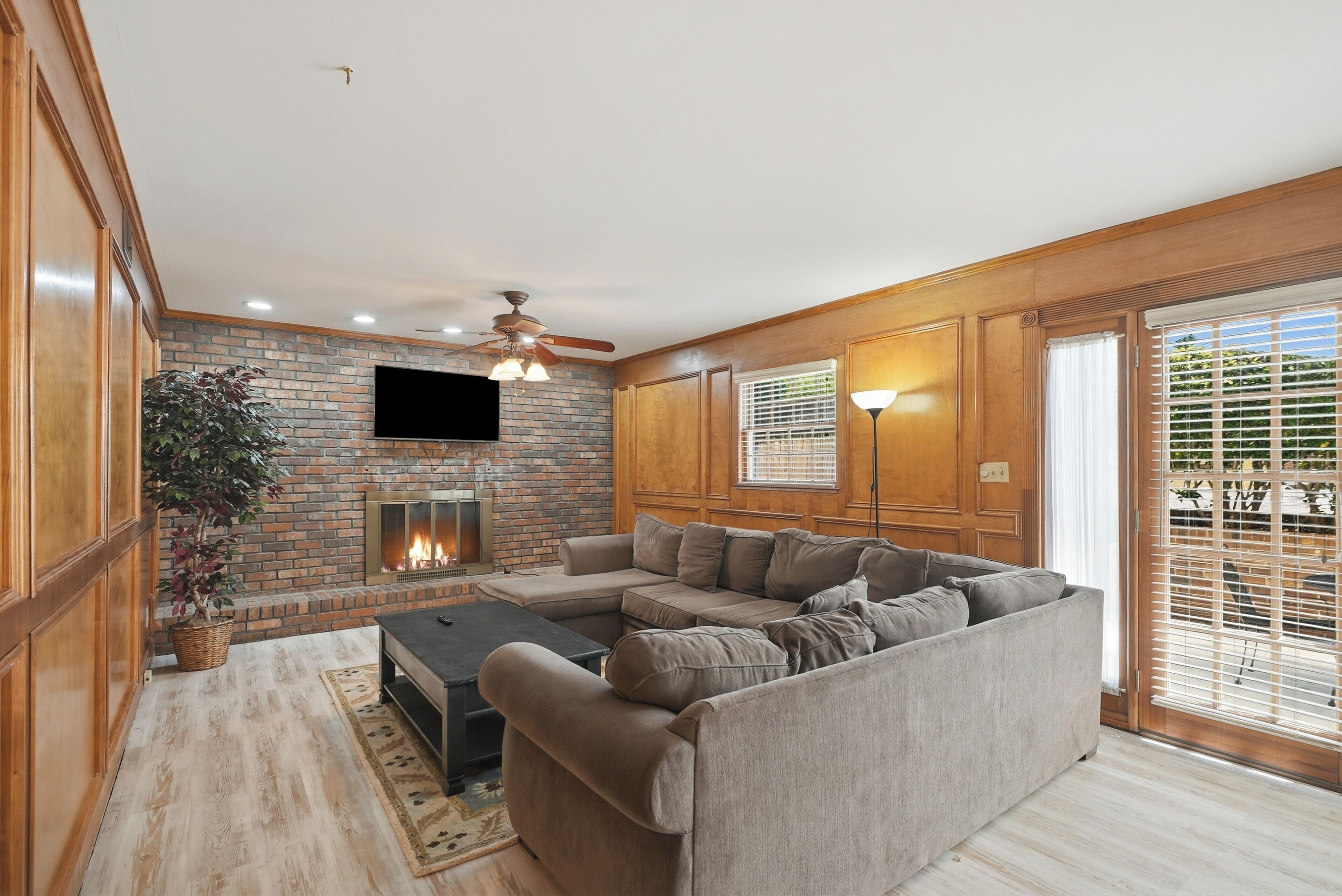 A living room with a fireplace, a sofa, a coffee table, and a television mounted on the wall.