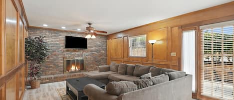 A living room with a fireplace, a sofa, a coffee table, and a television mounted on the wall.