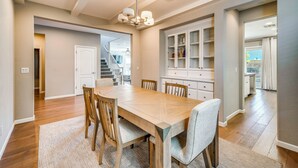 Un coin repas avec une table et des chaises en bois, un lustre et un meuble encastré doté d’étagères.