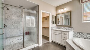Une salle de bain avec une douche à parois de verre, un meuble-lavabo avec un miroir et une baignoire.