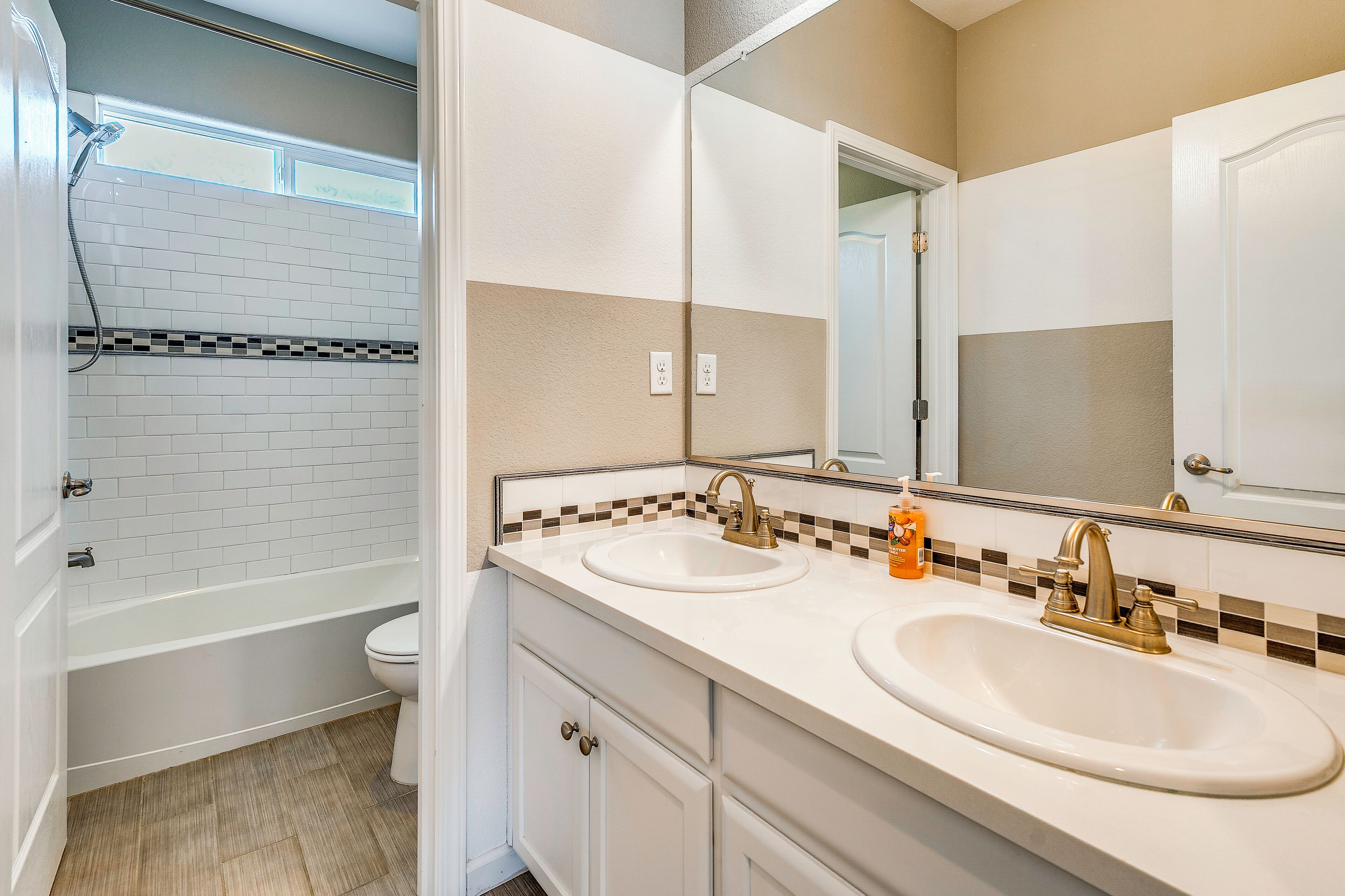 A bathroom with two sinks, a shower, and a toilet.