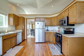 A kitchen with wooden cabinets, stainless steel appliances, and a large refrigerator. - 5BR Home Close to Moorhead Home & Fargo (Moorhead)