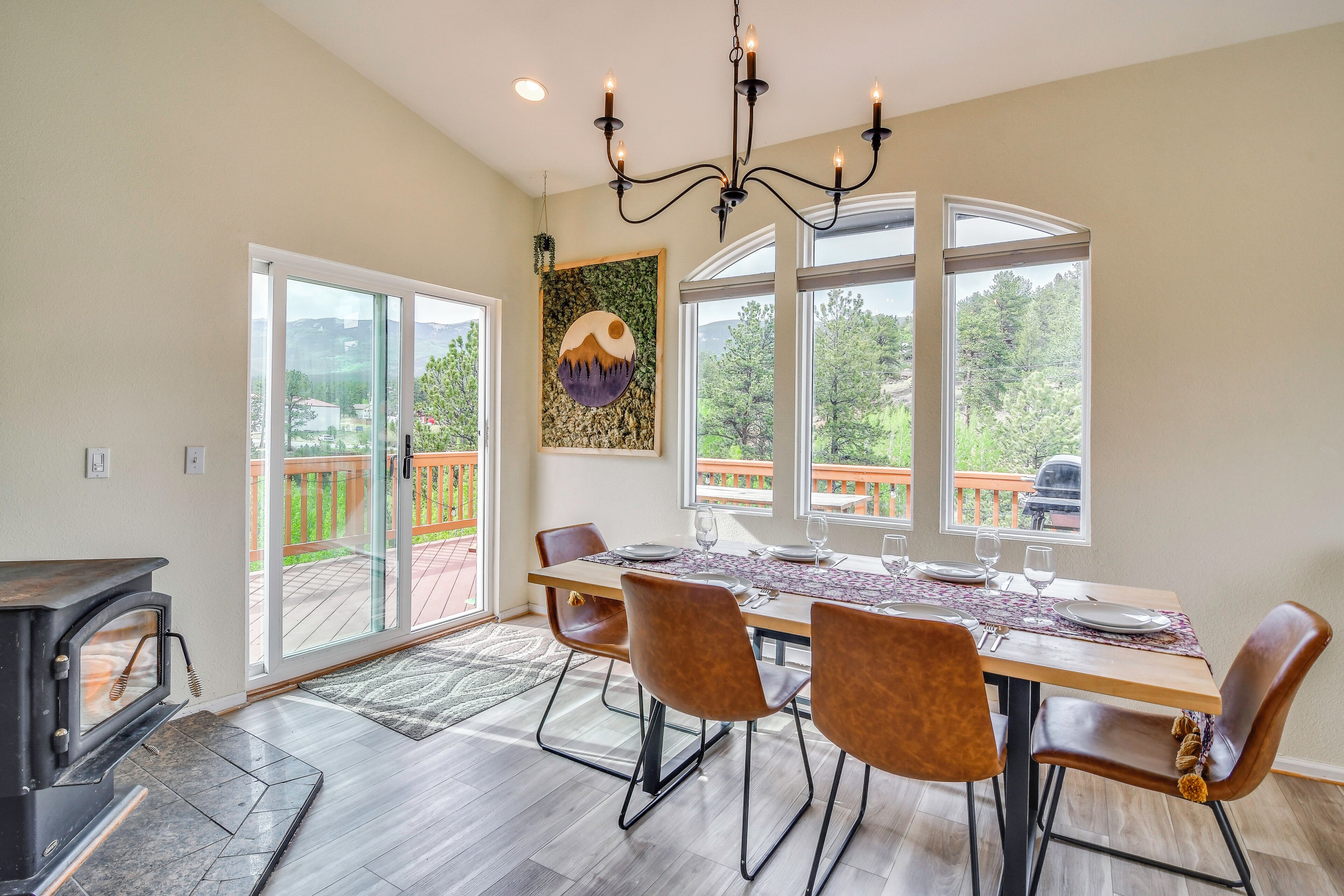 A dining area with a table set for four, a fireplace, and large windows with a view of the outdoors.
