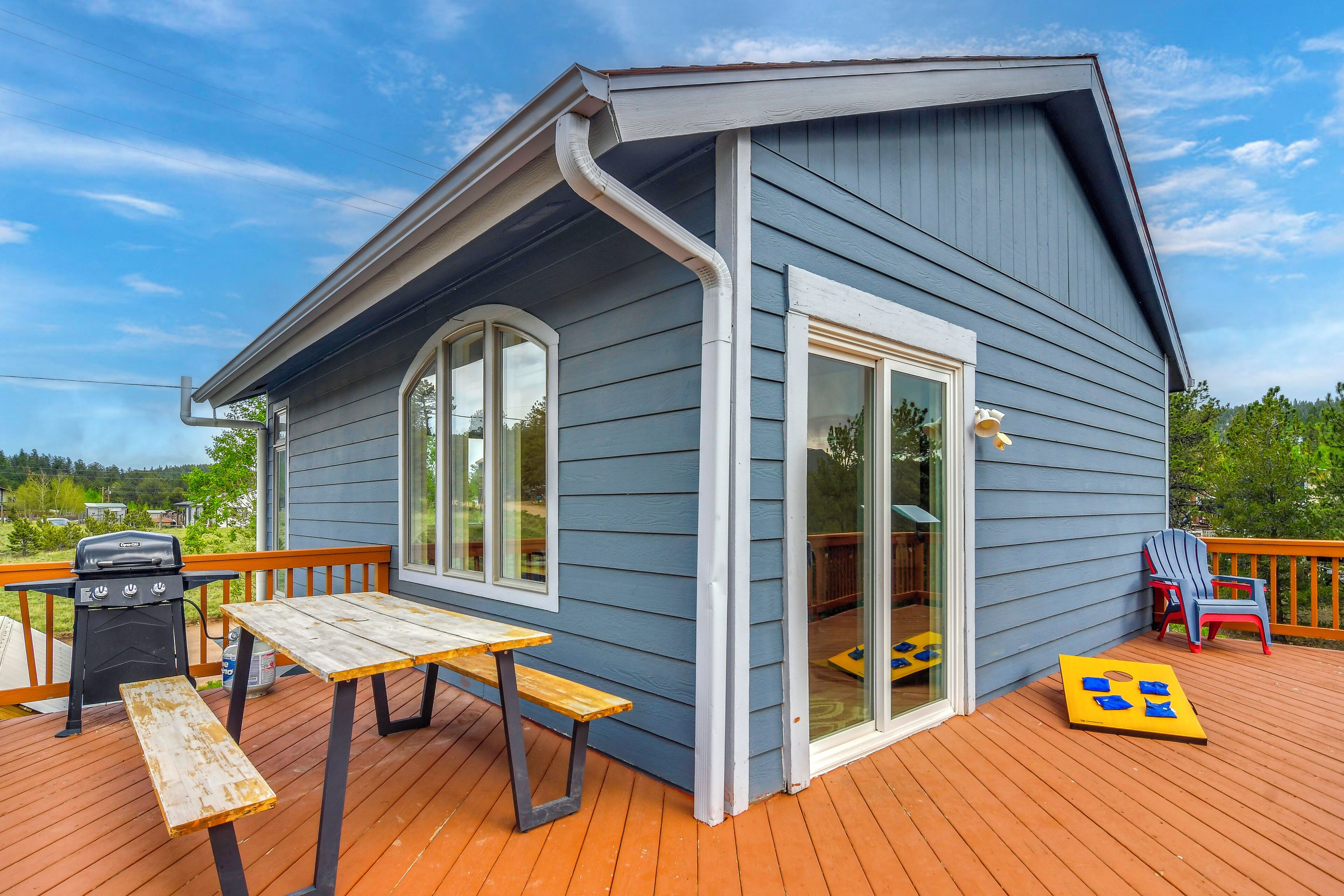 A house with a deck, a barbecue grill, and a table.