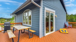 Ein Haus mit einer Terrasse, einem Grill und einem Tisch.