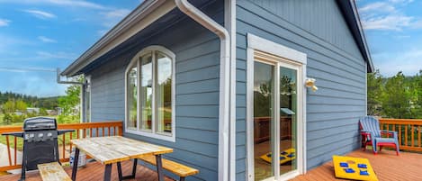 A house with a deck, a barbecue grill, and a table.