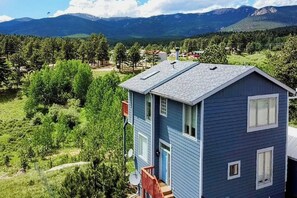 Ein zweistöckiges Haus mit blauer Fassade und roter Veranda, sowie einer Satellitenschüssel.