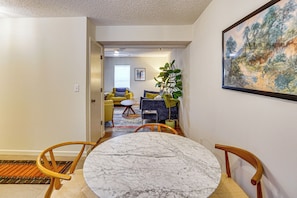 A hallway leading to a living room with a round marble table, yellow chairs, and a potted plant. - Remote Work Ready! Walkable Fayetteville Home (Fayetteville)