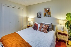 A hotel room with a bed, two bedside lamps, a potted plant, and two framed floral artworks on the wall. - Remote Work Ready! Walkable Fayetteville Home (Fayetteville)