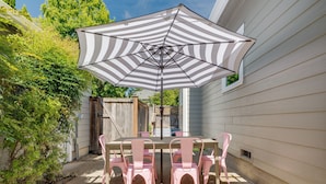 Eine Terrasse mit Tisch, Stühlen und einem Sonnenschirm, begrenzt durch einen Holzzaun.