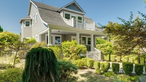 Ein zweistöckiges Haus mit einer Veranda, einem Schornstein und einem gepflegten Garten.