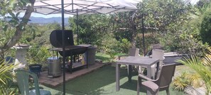 An outdoor patio with a grill, table, chairs, and an umbrella. - Welcoming 3-bedroom house in Guatape perfect for your getaway (Guatape)