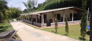 A single-story building with a covered patio area, a paved walkway, and a parked motorcycle. - Welcoming 3-bedroom house in Guatape perfect for your getaway (Guatape)