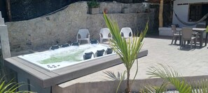 An outdoor hot tub with chairs around it, a stone wall, and a small table with chairs in the background. - Welcoming 3-bedroom house in Guatape perfect for your getaway (Guatape)