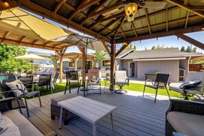 An outdoor patio with wooden furniture, a table, and umbrellas providing shade. - Napa Extended Stay: Private Pool, Garage Parking! (Napa)