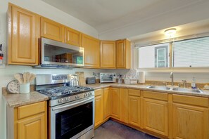 A kitchen with wooden cabinets, a stove, a microwave, a toaster, and a sink.