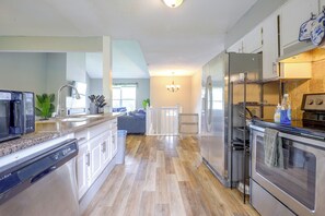 A modern kitchen with stainless steel appliances, a granite countertop, and a view to the living area. - 11 Mi to Overland Park: Olathe Mid-Term Stay (Olathe)