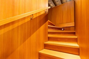 Eine Holztreppe mit Handlauf und einer Tür am oberen Ende.