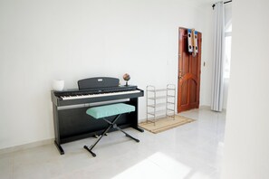 Ett piano med en pall, en jordglob och en hyllsektion i ett rum med ett klinkergolv och en dörr med gardiner.