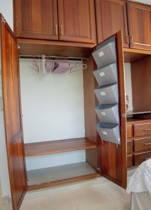 Ein hölzerner Kleiderschrank mit mehreren Fächern, darunter Kleiderstangen und Schubladen.