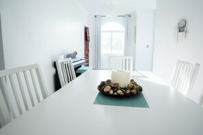 A dining area with a white table, chairs, a candle, and a bowl of nuts. - Lovely  apartment with AC in vibrant Your Paradise Coastal Retreat in Nagua (Nagua)