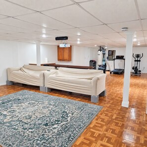 A room with a large, patterned rug, a sofa, and exercise equipment. - 6 Beds 5,000 SqFt Country Retreat: Sleeps the Whole Family w/ Resort Pool & Spa (Mohnton)