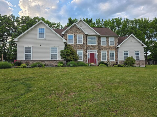 A two-story house with a stone facade and a red door. - 5,000 SqFt Country Retreat: Sleeps the Whole Family, Pool & Spa (Mohnton)