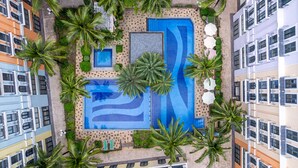 A rooftop pool surrounded by palm trees and modern buildings. - AMÉRYS Hotel Phu Quoc (Phu Quoc)
