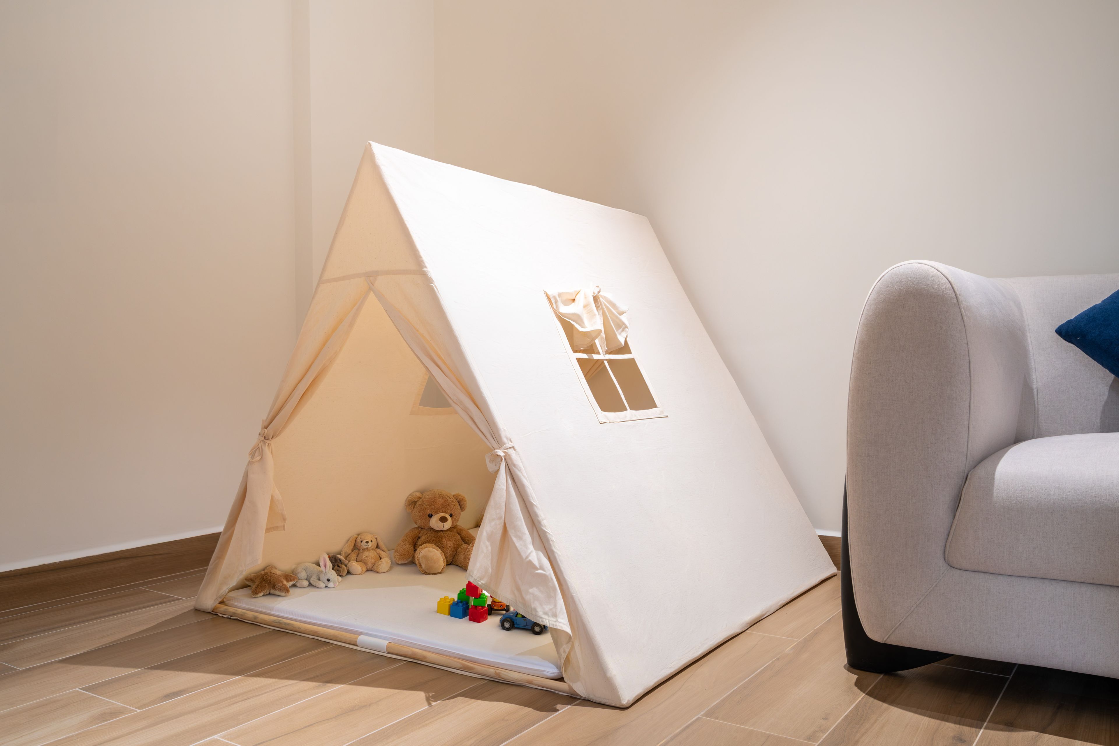 Un área de juegos con forma de tienda de campaña, con juguetes y un oso de peluche.
