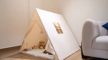 Un área de juegos con forma de tienda de campaña, con juguetes y un oso de peluche.