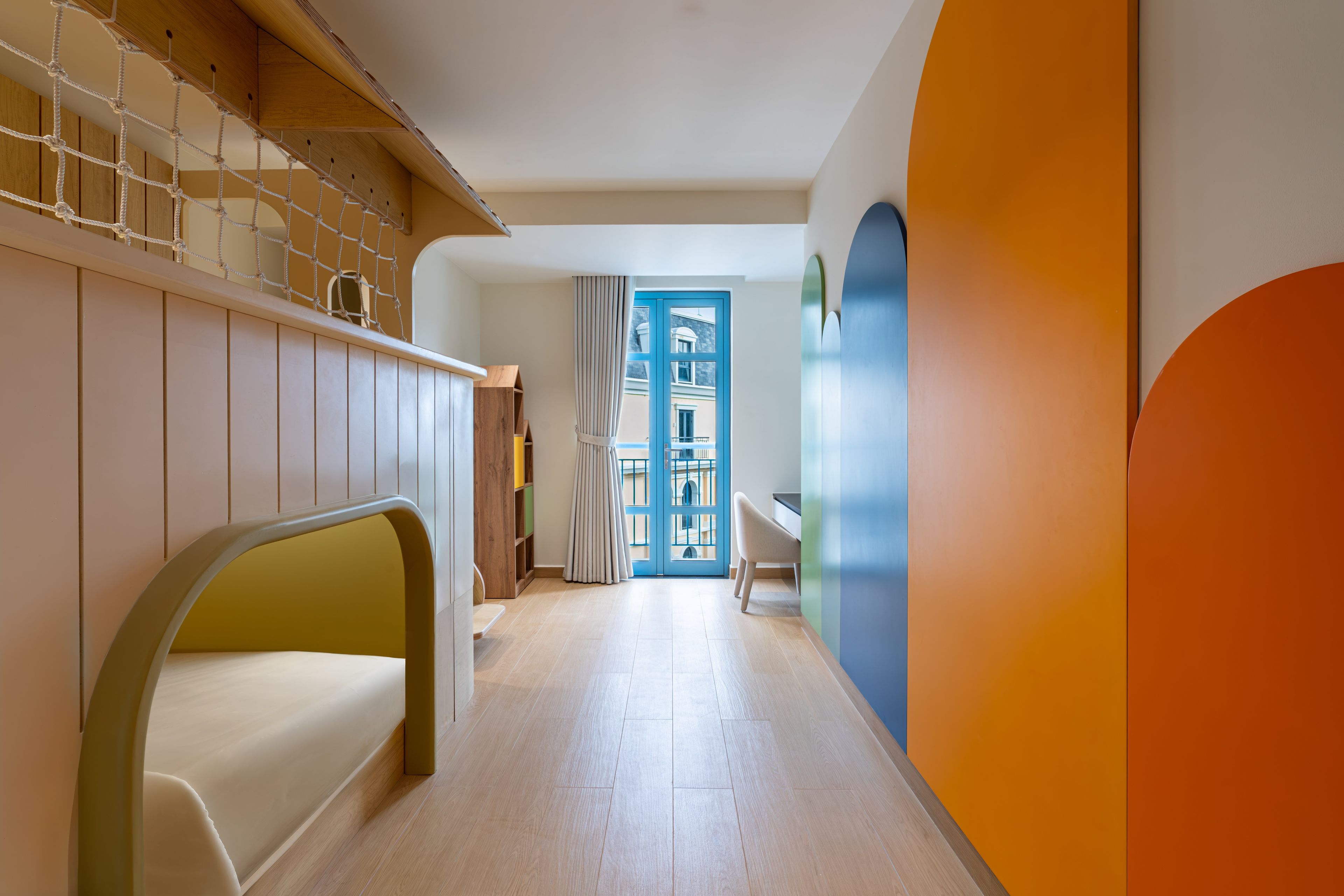 Un passadís amb una escala de fusta, una porta blava i una cadira blanca.